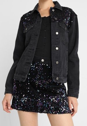 Sort denimjakke med palietdetaljer på skuldrene, kombineret med sort bluse med knapper og matchende sort mininederdel med palietter.
