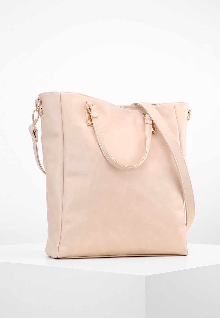 Jasnoróżowa torba typu tote ze skóry z dwoma uchwytami i odpinanym paskiem na ramię. Posiada elementy w odcieniu złota oraz gładkie, matowe wykończenie.