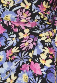 Blommigt tryckt tyg med rosa, gula och blå blommor på svart bakgrund. Har en texturerad väv och synliga sömmar.