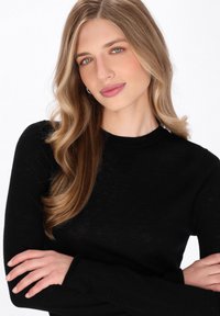 Zwarte lange mouwen shirt gemaakt van een lichtgewicht, licht gestructureerde stof. Heeft een ronde halslijn en een aangesloten silhouet, met eenvoudige details.