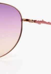 Roze gouden zonnebril met een gradient paarse lens. Heeft een strak, afgerond ontwerp en unieke gestructureerde pootaccenten.
