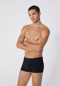 Caleçons boxers noirs en tissu lisse et extensible. La ceinture est élastique et le design présente une coupe ajustée sans motifs.