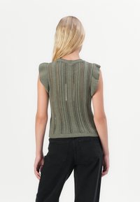 Top verde tricotat fără mâneci, cu dungi verticale și modele de lucru deschis. Decupaj și tiv striat, textură moale și siluetă ajustată.
