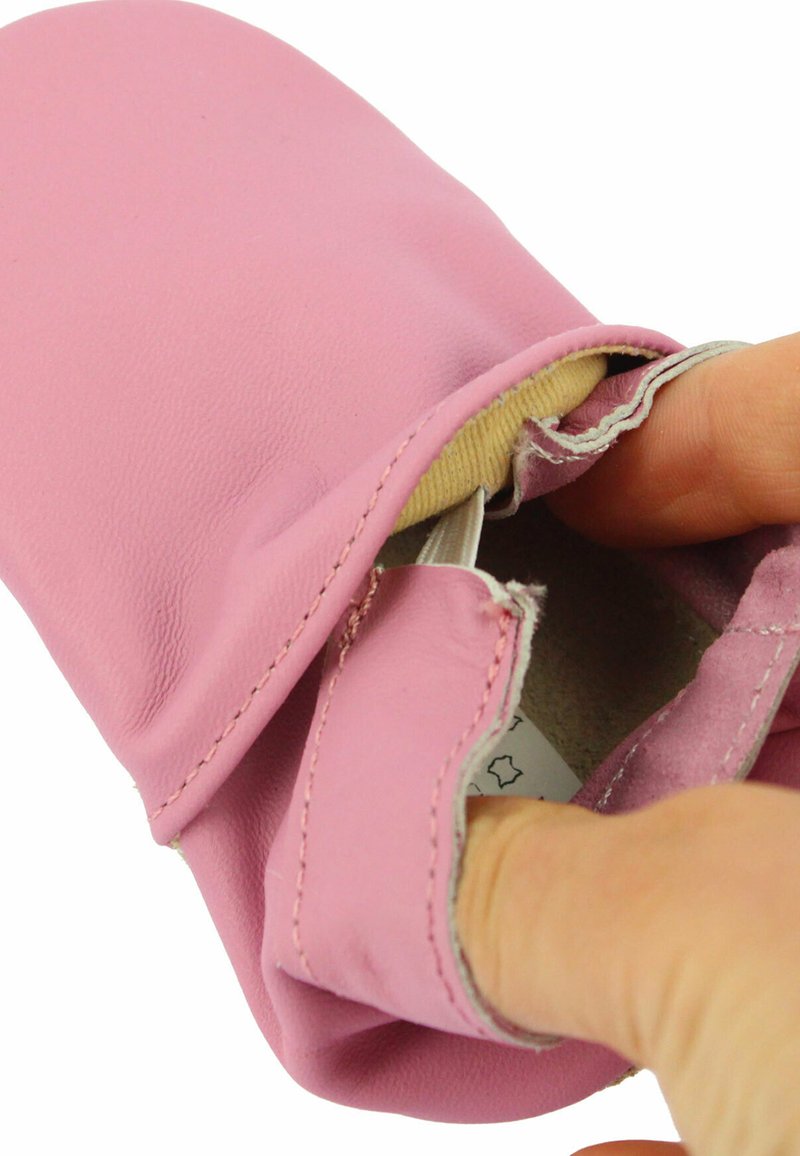 Pinker Leder-Slipper mit einem weichen Innenfutter. Die Öffnung zeigt nähtechnische Details und ein angebrachtes Etikett im Inneren.