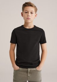 Svart bomulls-T-shirt med korta ärmar och rund halsringning, matchad med ljusgröna byxor. Enkel design, enfärgad, utan synliga mönster.