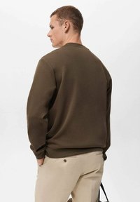 Olijfgroene sweatshirt met een ronde hals, lange mouwen en een relaxte pasvorm. Gemaakt van zacht materiaal, met minimale naden en een gladde textuur.