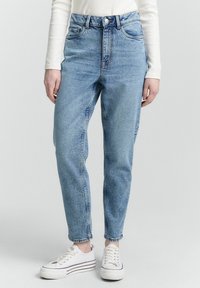 Jeans a vita alta di un azzurro chiaro, realizzati in denim, con design a gamba dritta e leggera scoloritura. Abbinati a sneakers bianche.