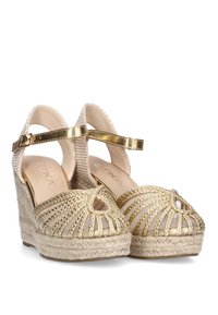 Sandalias de cuña con parte superior de tejido beige, correas doradas y plataforma de yute trenzado. Presenta recortes y un diseño de punta cerrada.