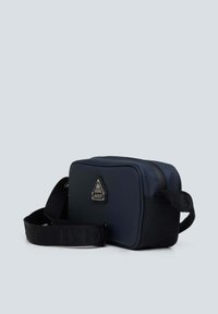 Borsa rettangolare blu navy realizzata in materiale liscio, con un logo ricamato e una tracolla nera regolabile con testo in rilievo. Chiusura con zip.