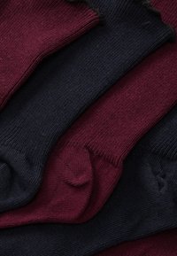 Βαμβακερές κάλτσες σε μπορντό και ναυτικό μπλε, με ριμπ ύφανση και λείο φινίρισμα, στοιβαγμένες σε επάλληλη διάταξη.