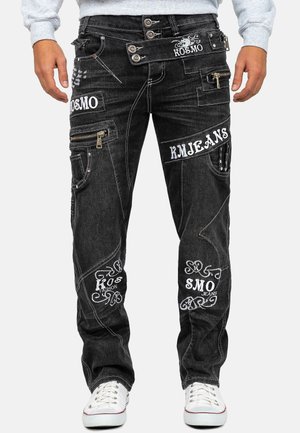 Schwarze Denim-Jeans mit mehreren weißen, bestickten Logos, Reißverschlüssen an den Oberschenkeln, aufgesetzten Taschen und Doppelknopf-Detail am Bund.