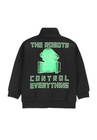 Czarna bluza z wysokim kołnierzem i oversize'owym krojem. Na plecach znajduje się zielony nadruk tekstowy: "ROBOTY KONTROLUJĄ WSZYSTKO" oraz ilustracja robota.