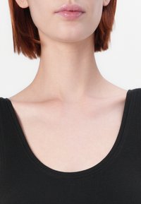 Top negru fără mâneci, cu decolteu larg și rotunjit; textură moale; amestec de spandex; design ajustat care evidențiază gâtul și umerii pe un fundal neutru.