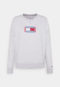 Felpa grigio chiaro con collo rotondo e maniche lunghe, caratterizzata da un logo rettangolare di Tommy Jeans in rosso, blu e bianco ricamato sul petto.