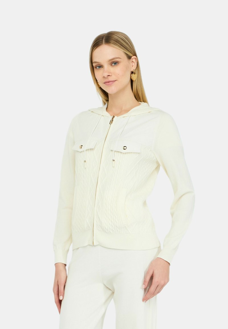 Felpa con cappuccio bianca in maglia con zip frontale, dotata di due tasche sul petto, pattern a rombi testurizzati e dettagli in metallo dorato.