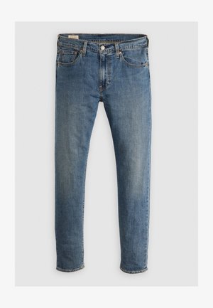 Jeans de ganga azuis com corte reto, apresentando cinco bolsos, fecho com zipper e rebites de cobre. O tecido tem um acabamento desbotado e ligeira textura.