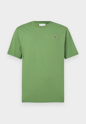 Roheline lühikeste varrukatega ümara kaelusega T-särk, millel vasakul rinnal väike tikitud Lacoste krokodilli logo.