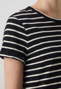 T-shirt à rayures noires et blanches, manches courtes, encolure ronde, fabriqué en tissu de coton doux, avec des rayures horizontales uniformément espacées.