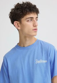 T-shirt en coton bleu clair avec col rond. Présente un petit logo blanc "Soulscape" sur la poitrine gauche. Manches courtes et coupe décontractée.