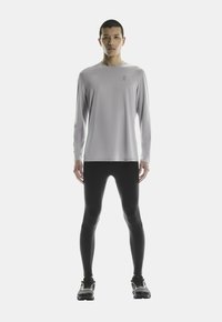 Ljusgrå långärmad träningströja, åtsittande svarta leggings och svarta löparskor. Minimalistisk design med subtil logotyp på tröjan.
