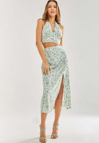 Two-piece floral outfit featuring a halter crop top and a mid-length skirt with a side slit. Fabric is lightweight with green and pink patterns.