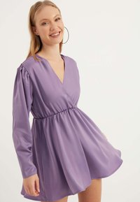 Lavendelfarbenes langärmliges Kleid mit tiefem V-Ausschnitt und geraffter Taille. Glattes, leichtes Material mit einem ausgestellten Rock und subtiler Glanz.