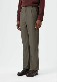 Olive green, pleated trousers with vertical pinstripes. Made of lightweight material, featuring a tailored fit and front pockets, paired with dark shoes.