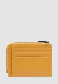 Cartera compacta de cuero marrón con cuatro ranuras para tarjetas en la parte frontal y un compartimento con cremallera en el borde superior sobre un fondo gris claro.