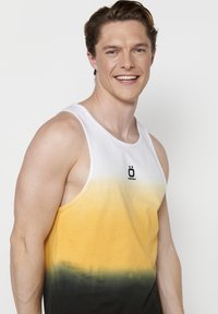 Valge Särgidükk, millel on kollasest roheline-mustani üleminek. Keskel on logo. Tehtud kergest kangast.