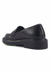 Black leather loafers with a rounded toe, decorative stitching, and a thick black sole featuring green accents.