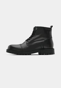 Botines de cuero negro hasta el tobillo con punta redonda, diseño de cordones, ojales grises en contraste y suela de goma resistente. Textura suave con acentos mínimos.