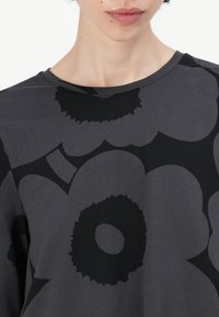 Gray t-shirt featuring large black floral patterns, round neckline, short sleeves, and smooth fabric texture.