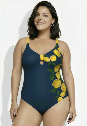 Lachende vrouw met schouderlang donker haar, die een marineblauw badpak draagt met een geel citroen- en bladprint aan de zijkant.