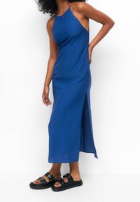 Blå maxiklänning med halterneck, texturerad tyg, sidoklyfta, när den kombineras med svarta platåsandaler med spänne.