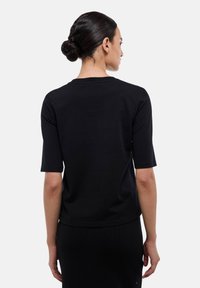 T-shirt noir à manches courtes avec un col rond, fabriqué en tissu doux, présentant un ourlet droit et une texture lisse.