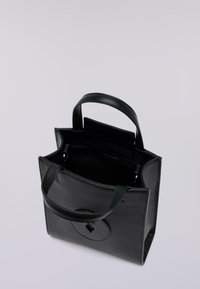 Czarna skórzana torba typu tote z dwoma krótkimi uchwytami, o prostokątnym kształcie, z okrągłym emblematem na przodzie i otwartą górą, ukazującą przestronne wnętrze.