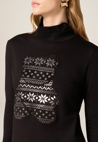 Czarny golf z nadrukiem niedźwiedzia wykonanego ze srebrnych i białych wzorzystych elementów, prezentujący motywy śnieżynek i geometryczne.