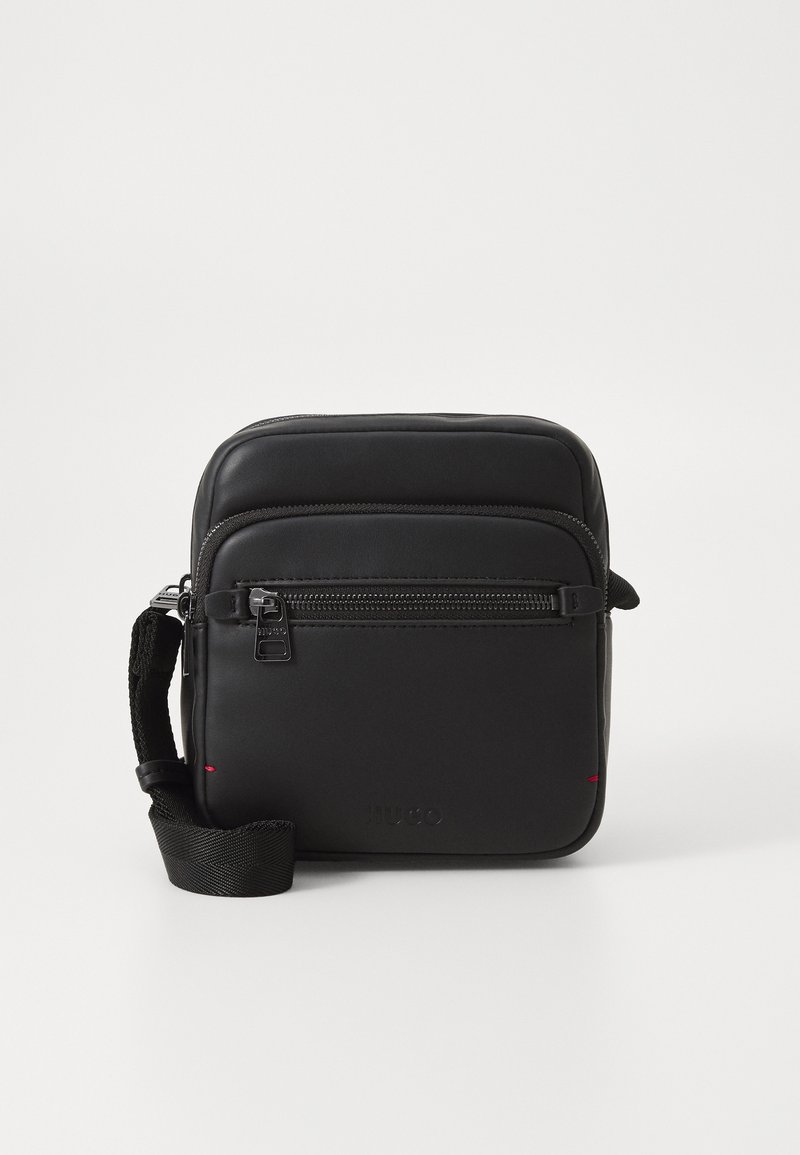 Borsa a tracolla in pelle nera con tasca frontale con zip, tracolla regolabile e logo impresso, caratterizzata da una texture liscia e un design semplice.