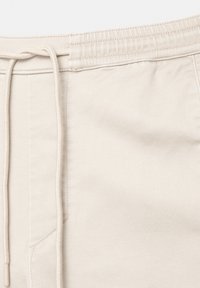 Beige bomullsblandning shorts med resårmidja, dragsko, sidoficka och slät textur.