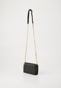 Bolsa de ombro em couro preto com uma alça de corrente dourada e fecho com zipper. O design é retangular com uma textura suave.