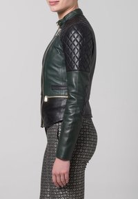 Černá a zelená kožená bunda s prošívanými černými rukávy, stojáčkovým límcem, předním zipem a postranními kapsami. Texturovaný a dobře padnoucí design.
