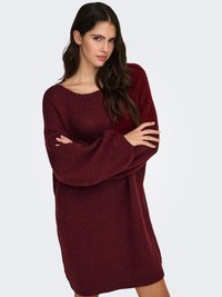 Vestido suéter de punto burdeos con ajuste holgado, escote ancho tipo barco y mangas largas. Tela texturizada con un patrón acanalado.