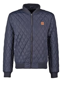 Námořnická prošívaná bunda s ribbovaným límcem, manžetami a lemem. Obsahuje přední zip a malou nášivku s logem na levé hrudi.