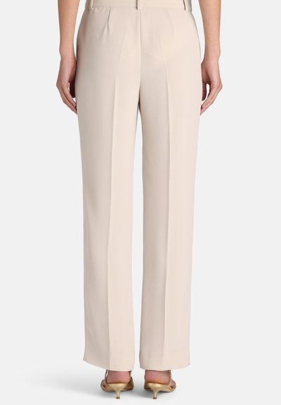 Pantalon beige clair sur mesure avec coupe droite, devant plissé et texture lisse. Présente des détails minimalistes et pas de poches visibles.