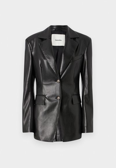 Must valge nahast bleiser, millel on lõigatud krae, kaks esikotti, ühe nööpiga kinnitamine ja kergelt kohandatud istuvus. Sile tekstuur.