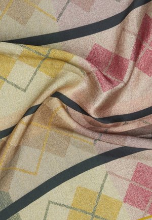 Miękki materiał z geometrycznym wzorem żółtych, czerwonych i beżowych kwadratów przeciętych zakrzywionymi czarnymi liniami, pokazany z naturalnymi fałdami.
