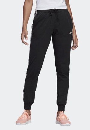 Pantalons de sport noirs dans une coupe décontractée avec des poignets et une taille élastiques, présentant des bandes blanches sur les côtés et un logo brodé sur la cuisse.