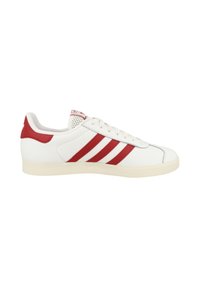 White sneaker with three red stripes, smooth leather upper, padded collar, and textured rubber sole. Features contrasting red heel cap.