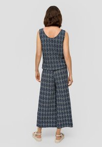 Ensemble deux pièces bleu marine à motifs comprenant un haut sans manches et un pantalon à jambes larges en tissu doux, avec une coupe ample et un motif floral.