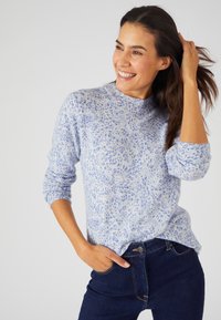 Helles blaues gemustertes Sweater aus weichem Stoff, mit Rundhalsausschnitt und langen Ärmeln, kombiniert mit dunkler Jeans.